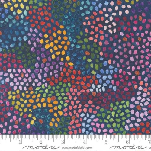 Colorful polka dot pattern fabric with an array of multicolored dots in pink, yellow, blue, green, purple, and red on a dark background with a ruler at the bottom.
