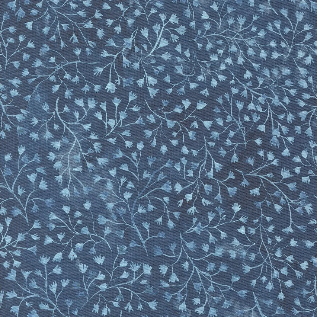 Close-up of blue fabric with a floral pattern of small, light blue flowers and winding vines.