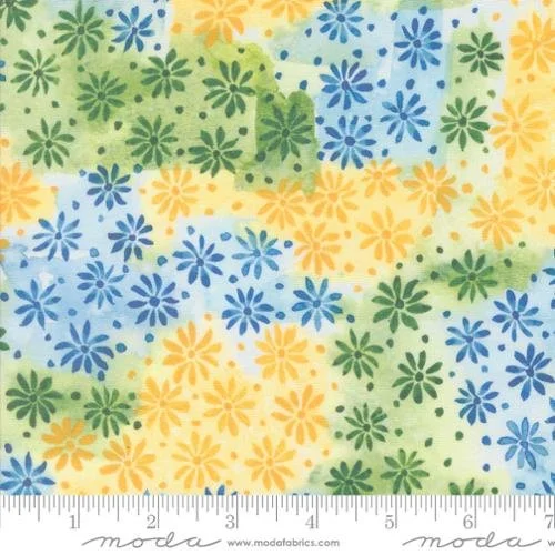 Close-up of a colorful floral fabric pattern with yellow, blue, and green flowers on a light background, featuring a ruler at the bottom for scale.