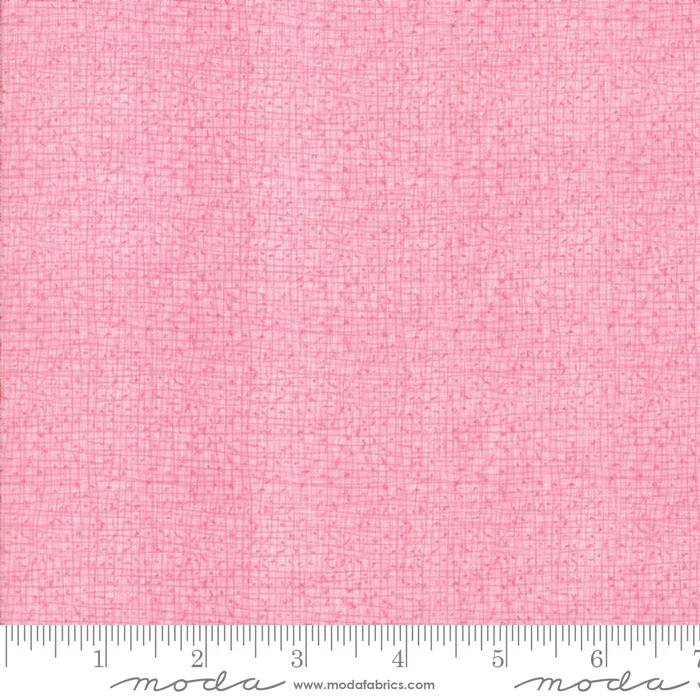 Close-up image of pink fabric with a subtle textured pattern and a ruler at the bottom showing measurements in inches.
