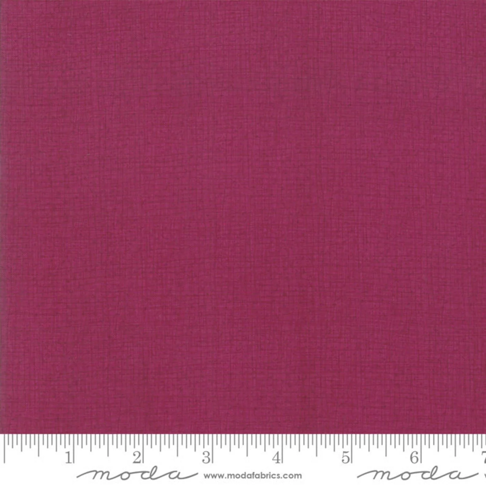 Close-up of a pink fabric with a subtle woven texture. Ruler at the bottom showing inches, with the fabric extending beyond the frame.