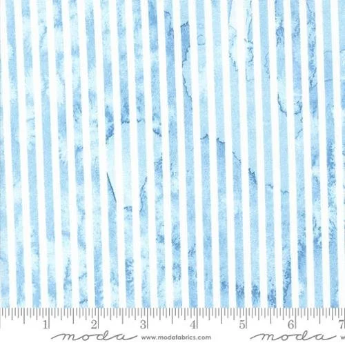 Close-up of a fabric with light blue and white vertical stripes and subtle marbling pattern, with a ruler at the bottom for scale.