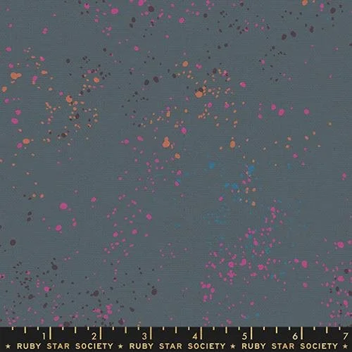 Close-up of a painted surface with multicolored splatters on a gray background, with a ruler at the bottom showing measurements in inches.