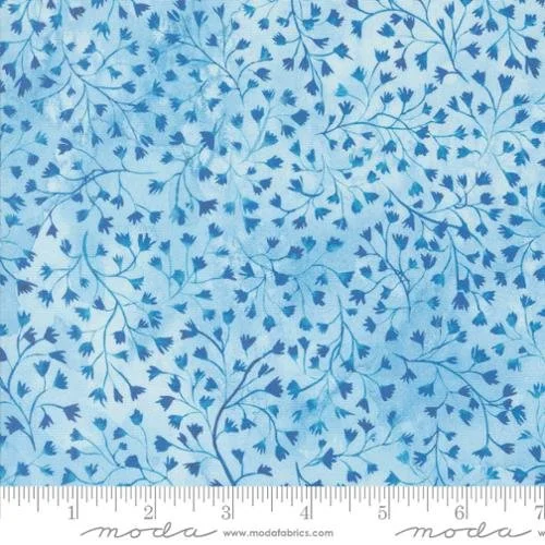 Blue fabric with a pattern of small, dark blue leaves and thin branches, and a measurement ruler at the bottom.