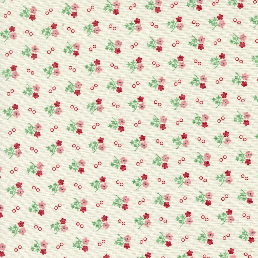 A fabric with a pattern of small pink and red flowers with green leaves and red circles scattered throughout.
