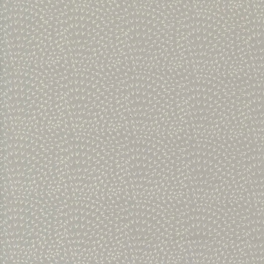 Close-up of textured fabric with small embroidered white triangles on a beige background.