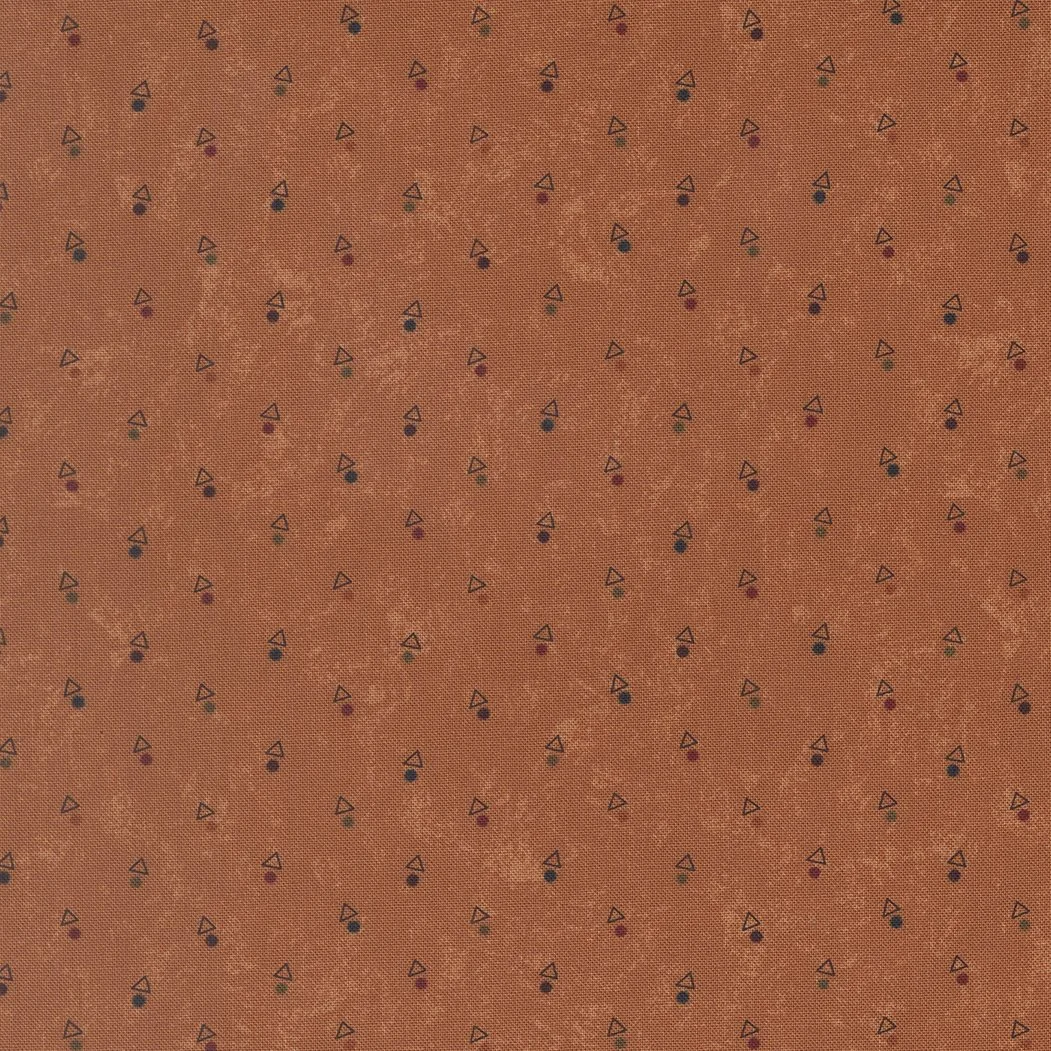 Orange fabric with small, multicolored geometric patterns including triangles and dots.
