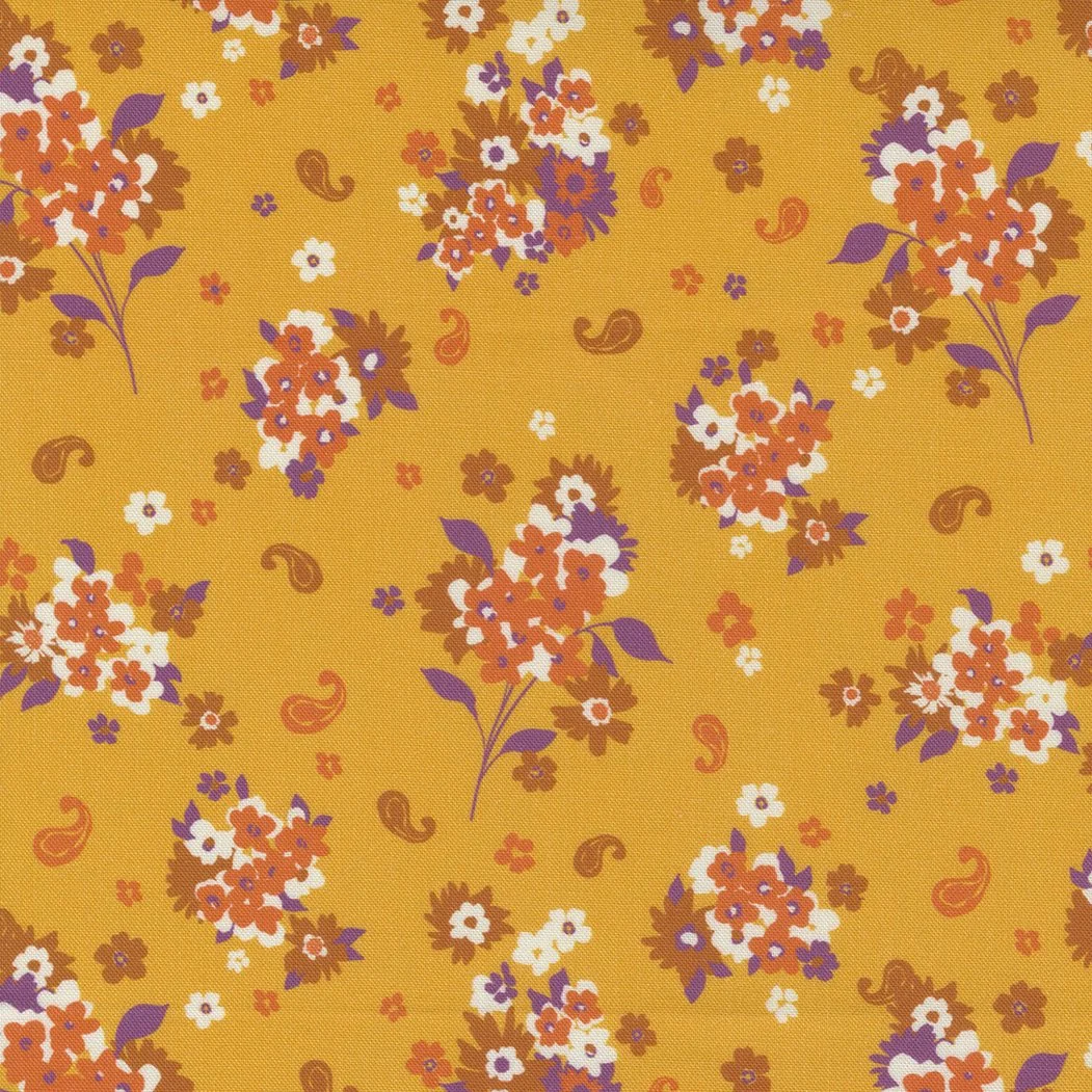 Yellow fabric with a floral pattern of small orange, white, purple, and brown flowers, along with purple leaves and orange paisley shapes.