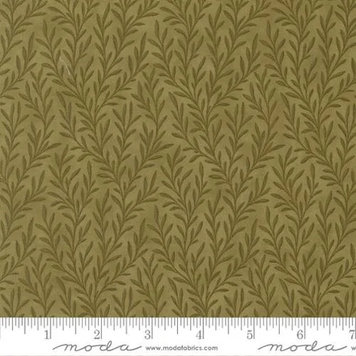 Close-up of fabric with a pattern of green leafy vines on a beige background, with a ruler at the bottom showing inches.