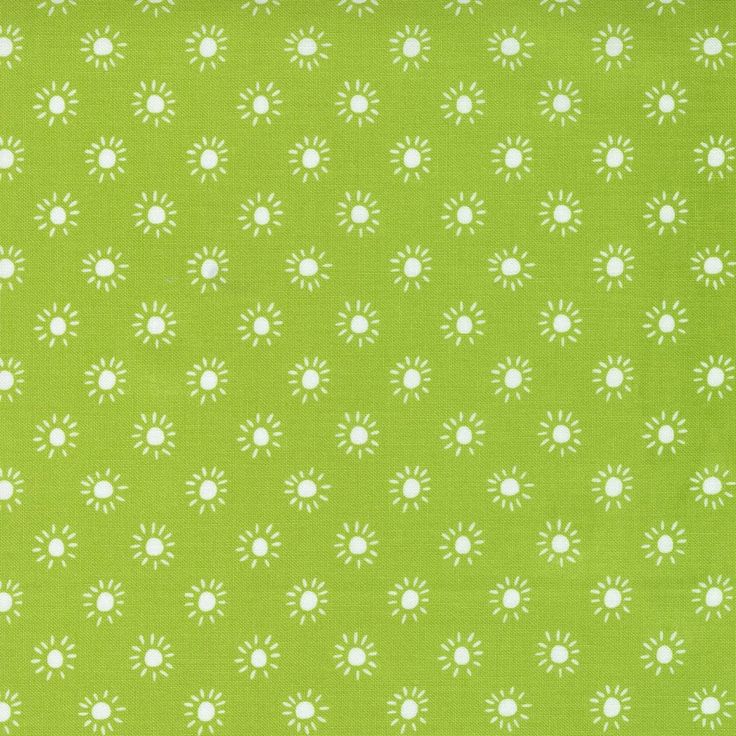 Close-up of a green fabric with a repeating pattern of small white suns.