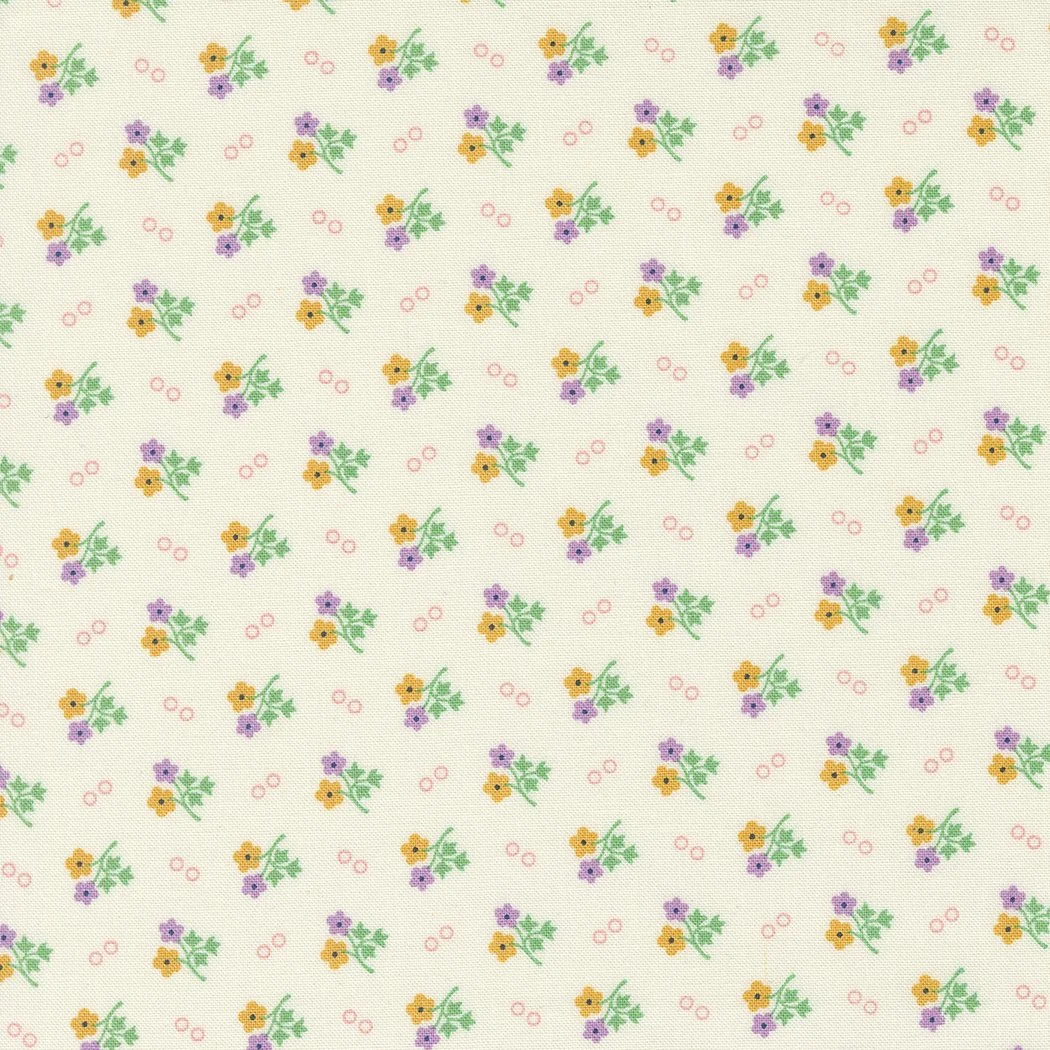 A patterned fabric with small yellow and purple flowers and pink circles on a white background.