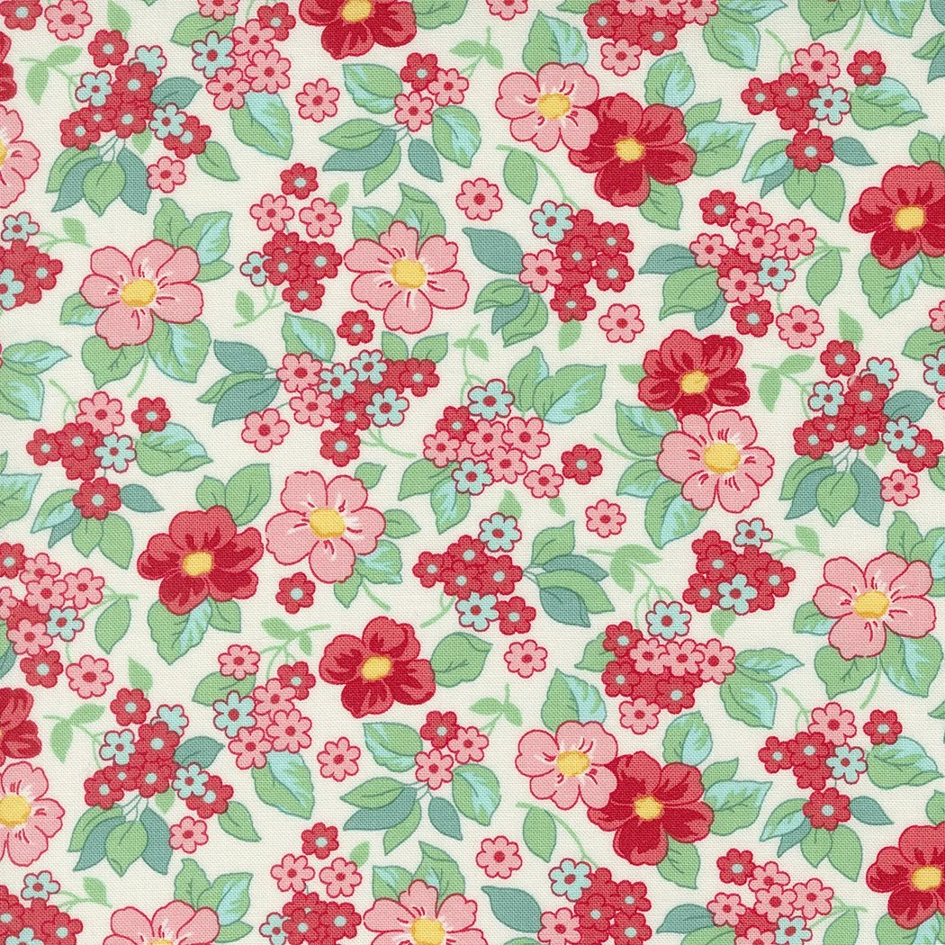 A floral fabric pattern with pink, red, and light blue flowers and green leaves on a cream background.