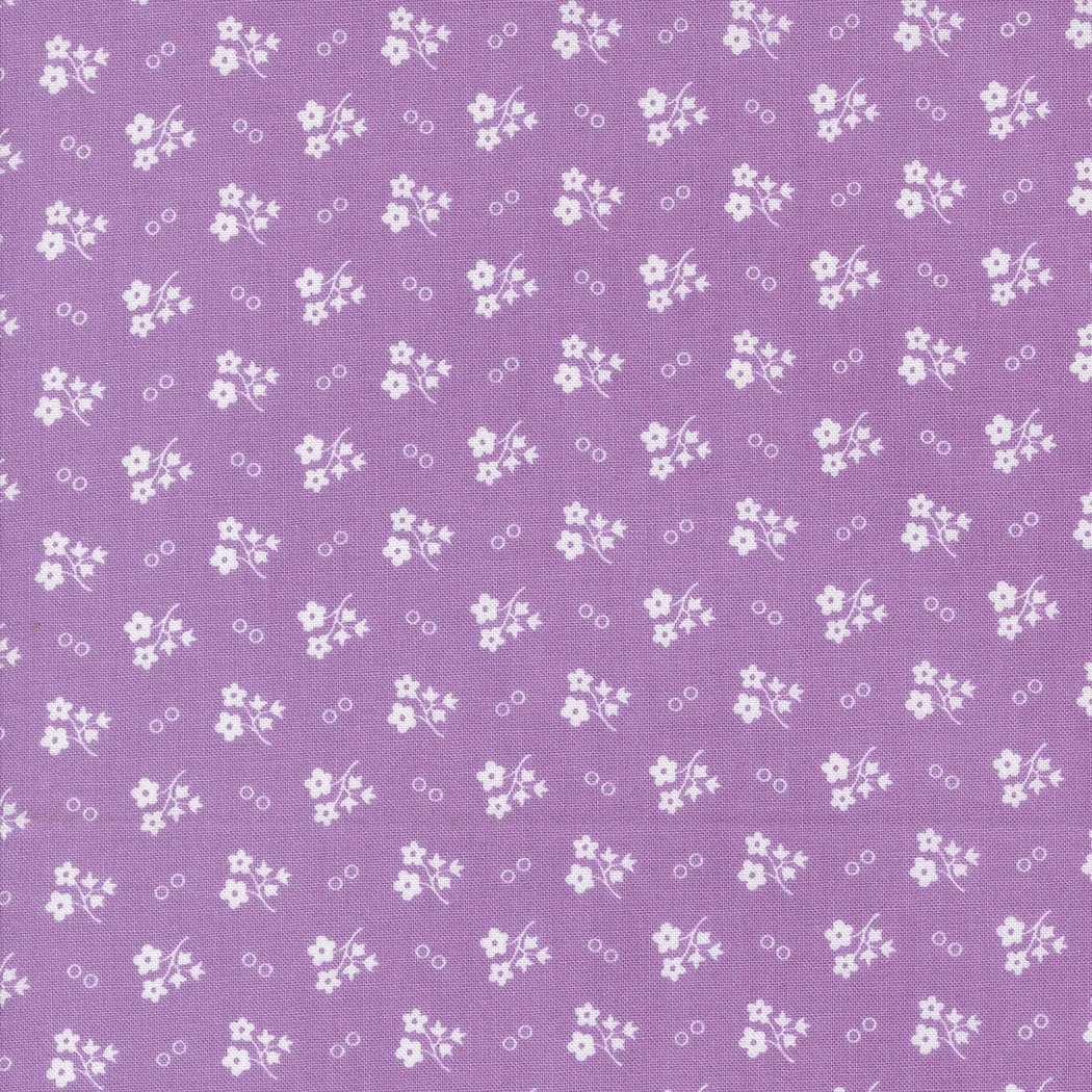 A fabric pattern with small white flowers and circles on a purple background.