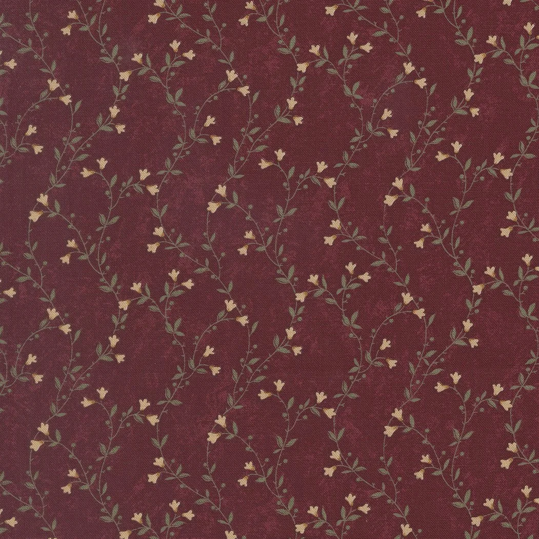 Patterned red fabric with small yellow flowers and green leaves arranged in a repeating vine design.