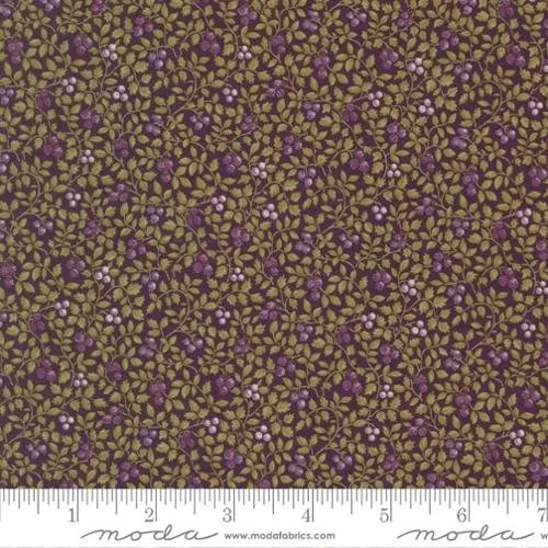 Close-up of fabric with a floral pattern featuring small purple, white, and yellowish-green flowers and leaves, with a ruler at the bottom indicating measurements in inches.