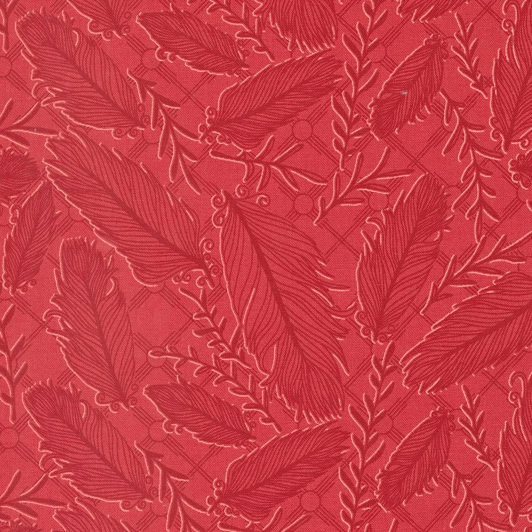 Close-up of red fabric with a pattern of embroidered feathers and branches.