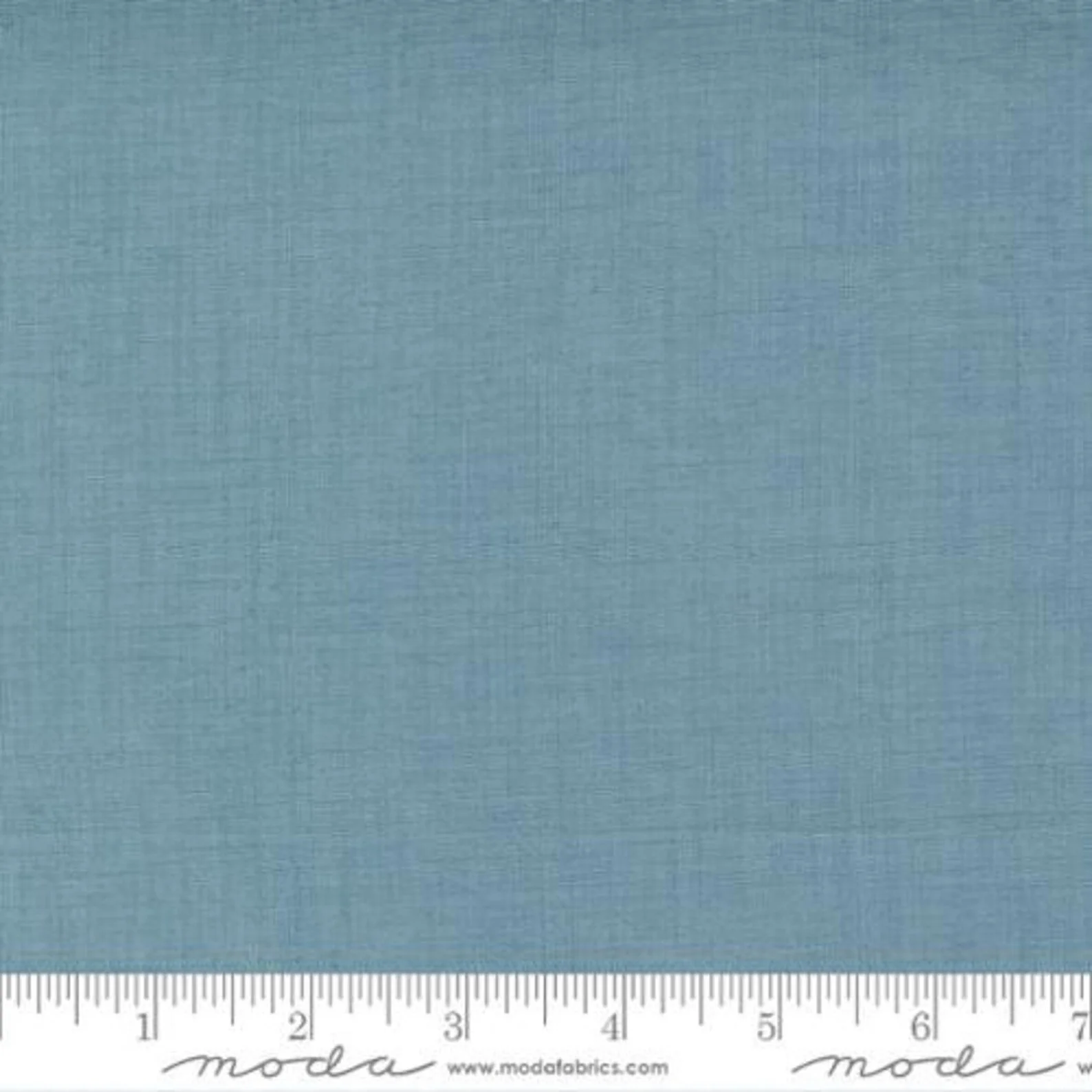 A light blue fabric sample with a subtle woven texture, placed above a ruler for size reference.