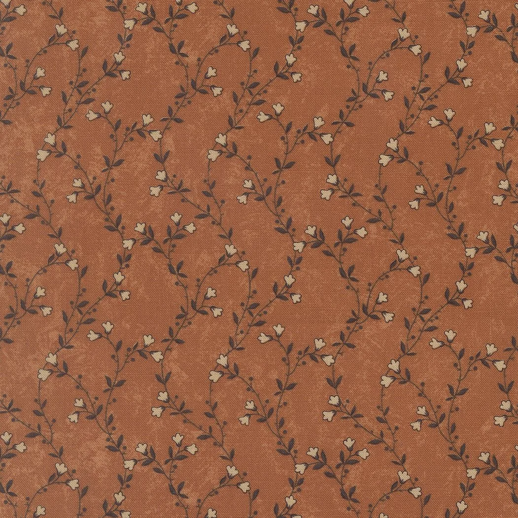 A fabric with a pattern of small cream-colored flowers and dark leaves on a textured rust-colored background.
