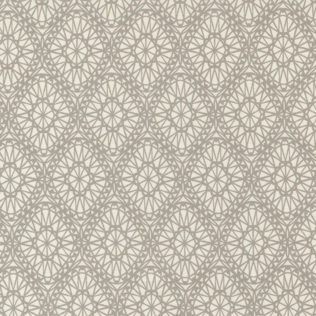 A fabric with a beige background and a repeating geometric pattern of interlocking star shapes in a darker beige color.