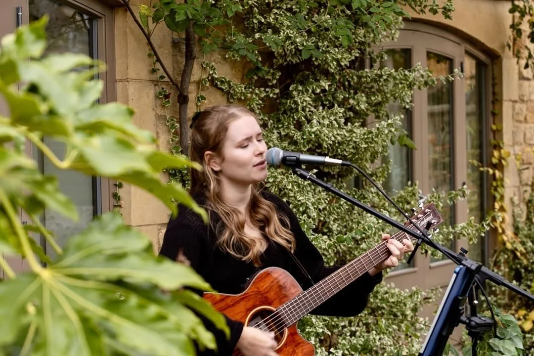 Poppy Rose performing with acoustic guitar at wedding reception