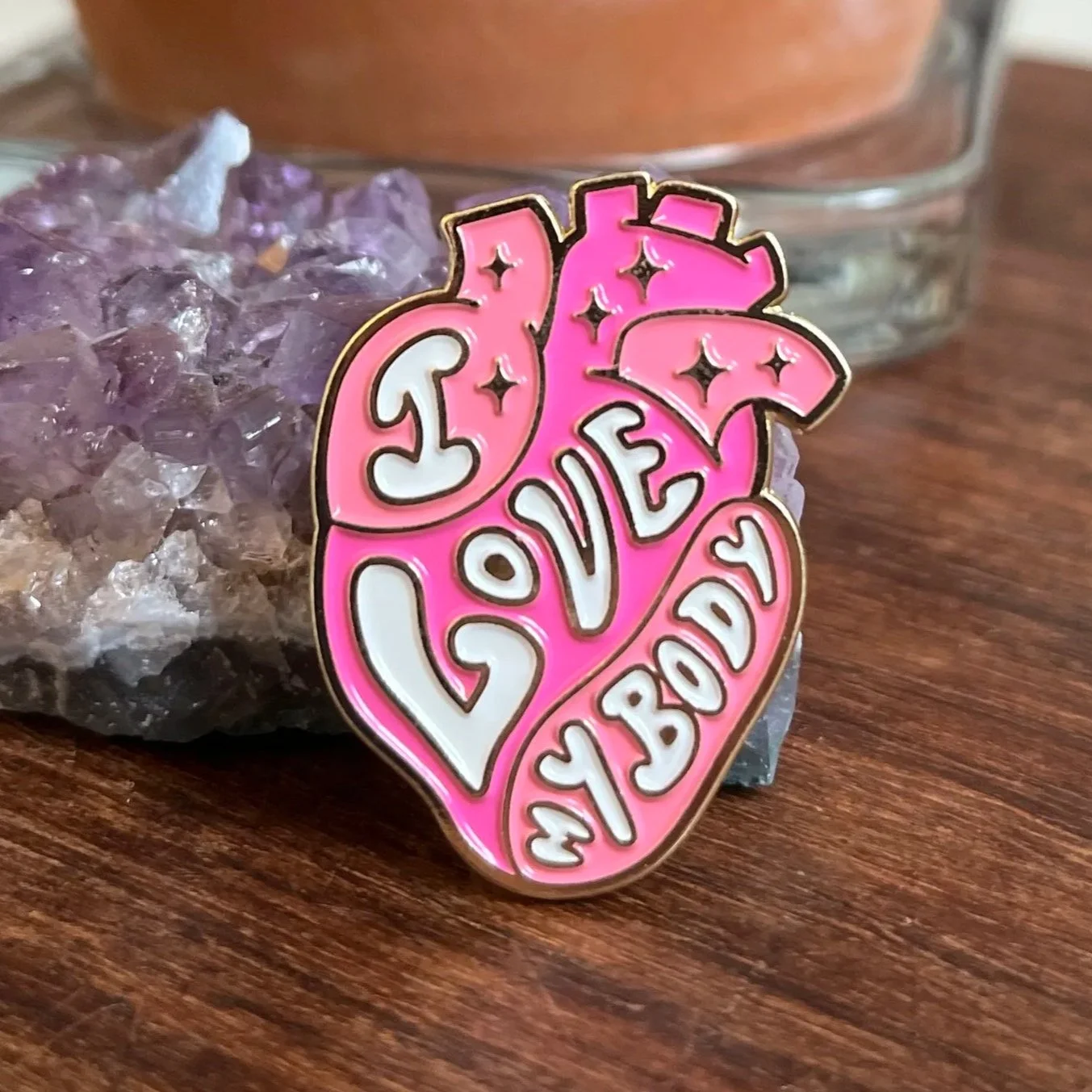 pink metal enamel pin badge in the shape of a anatomical heart reading "I Love My Body" with gold sparkles