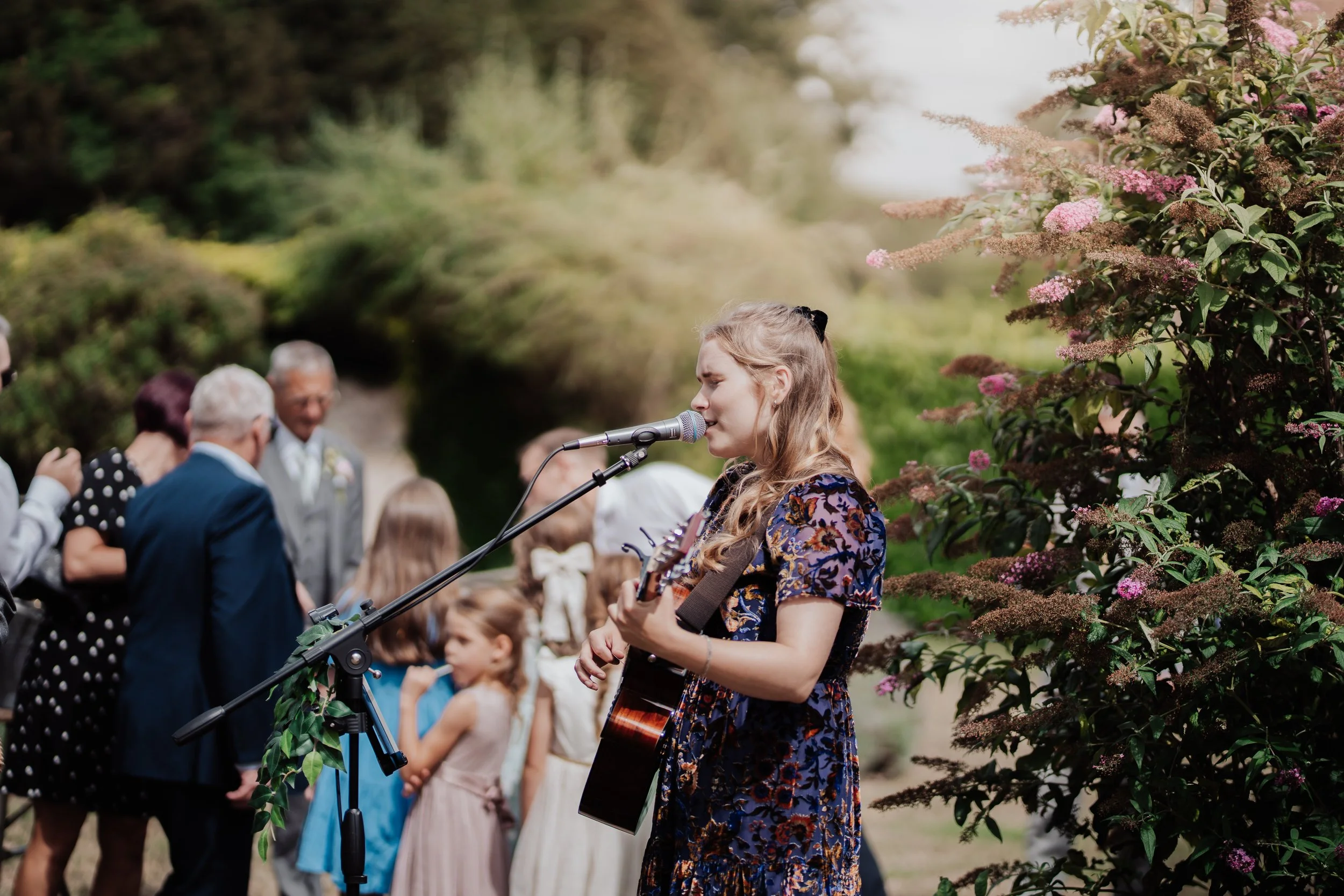 poppy rose singing at an outdoor wedding drinks reception in the summer