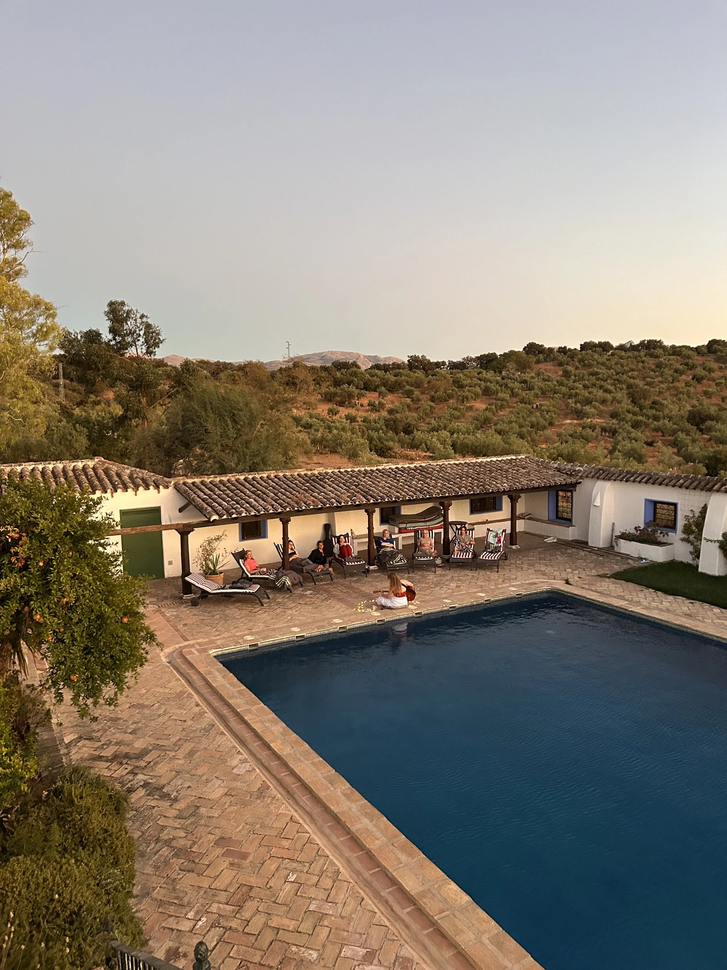 Poppy rose performing acoustic music pool-side at a yoga retreat in Spain
