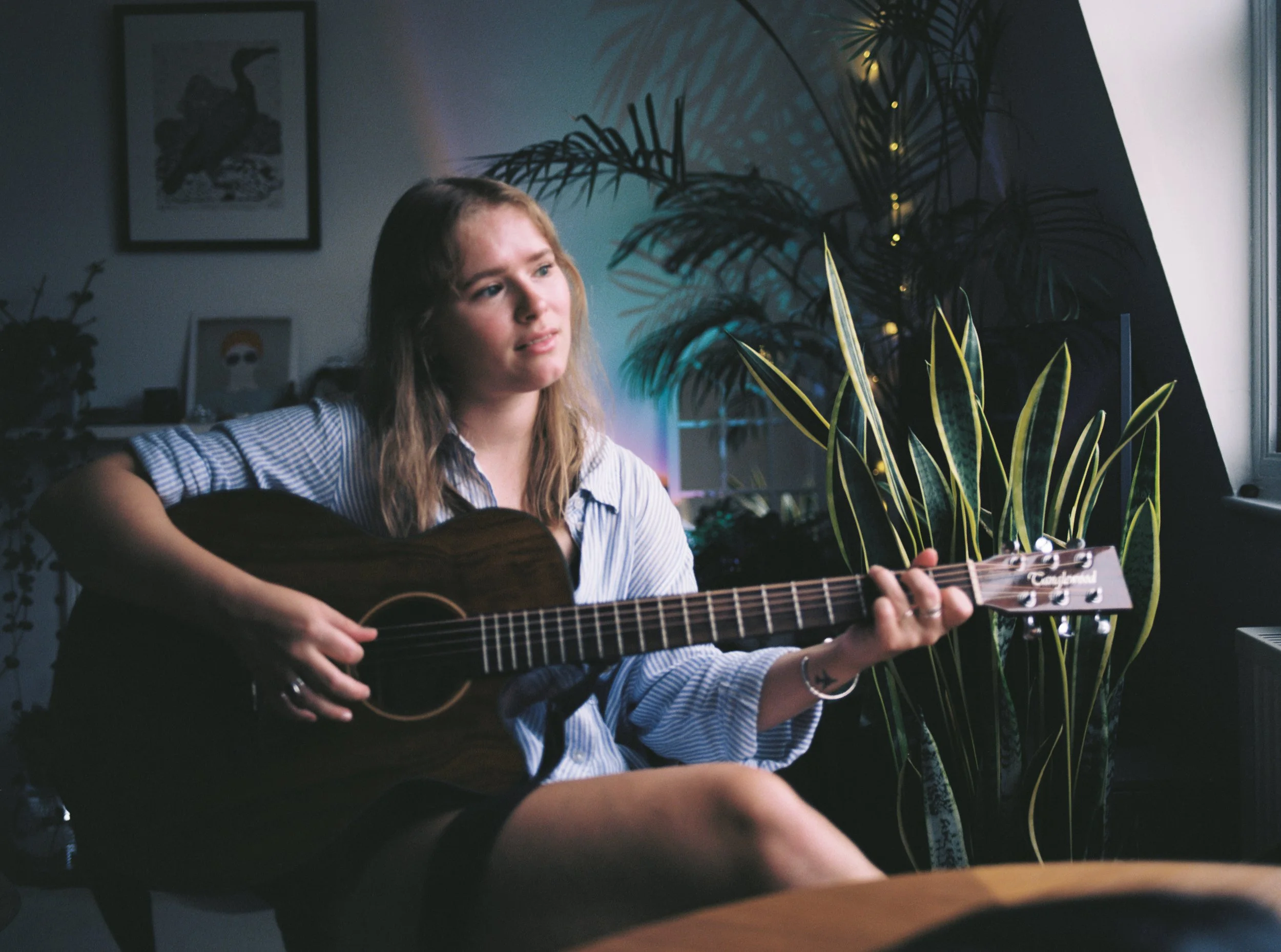 poppy rose playing acoustic guitar in a cosy room
