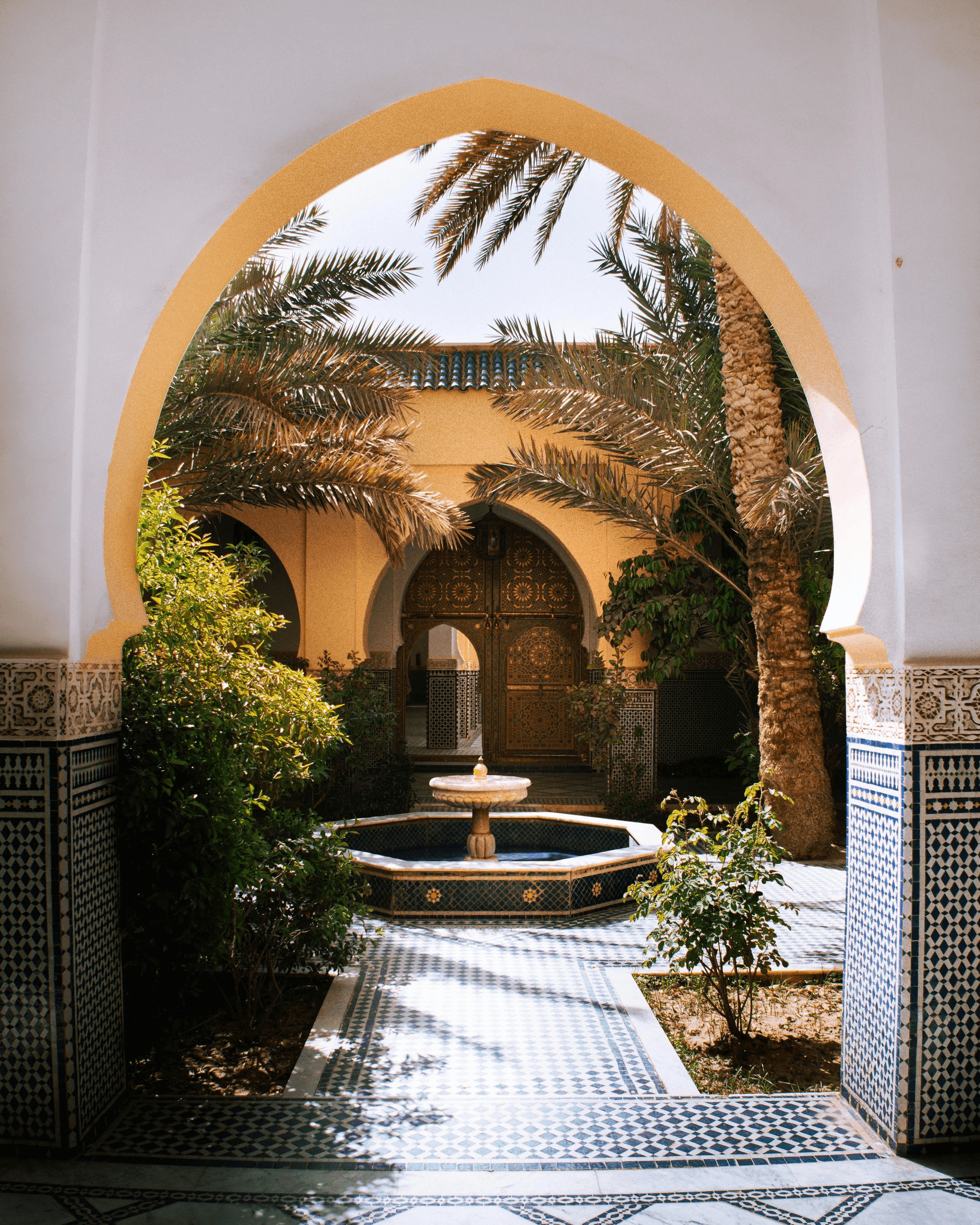 Moorish archway opening onto a courtyard with a fountain and palm trees