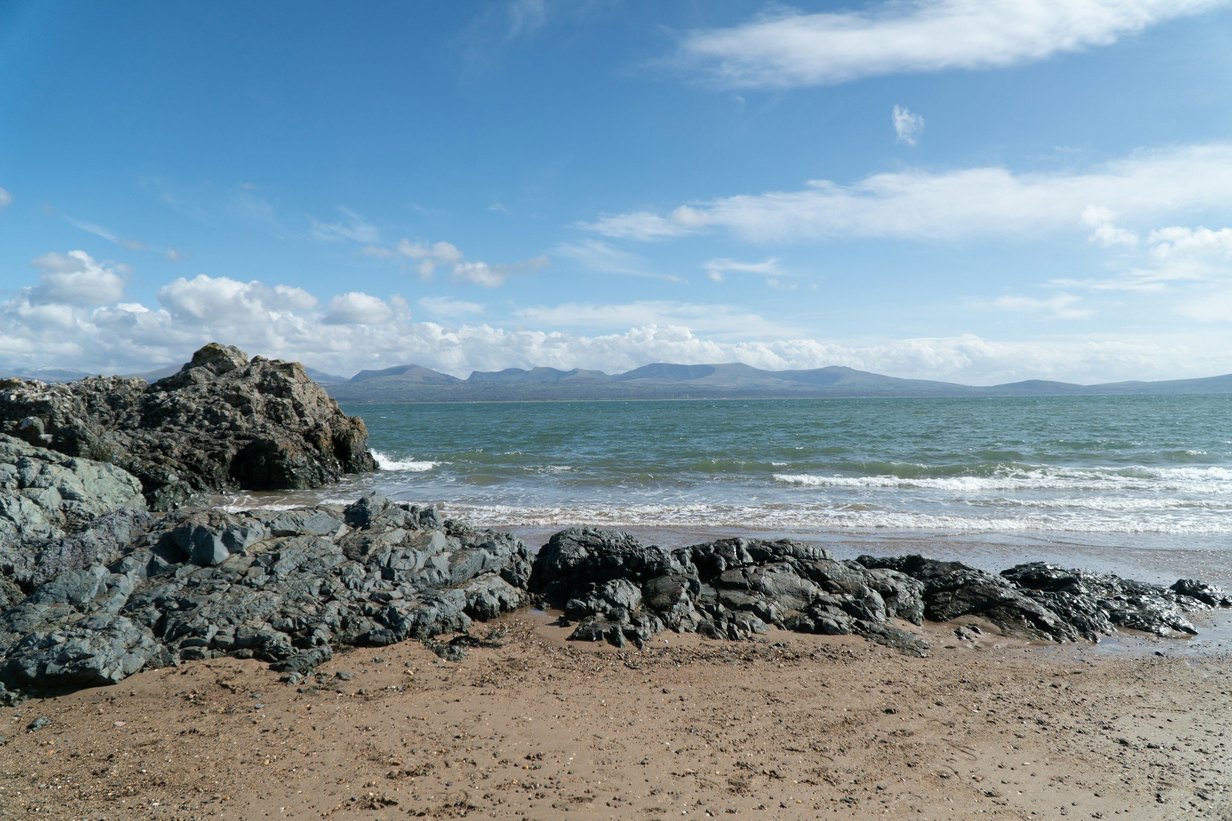 Wide sandy beach with distant mountains across the water