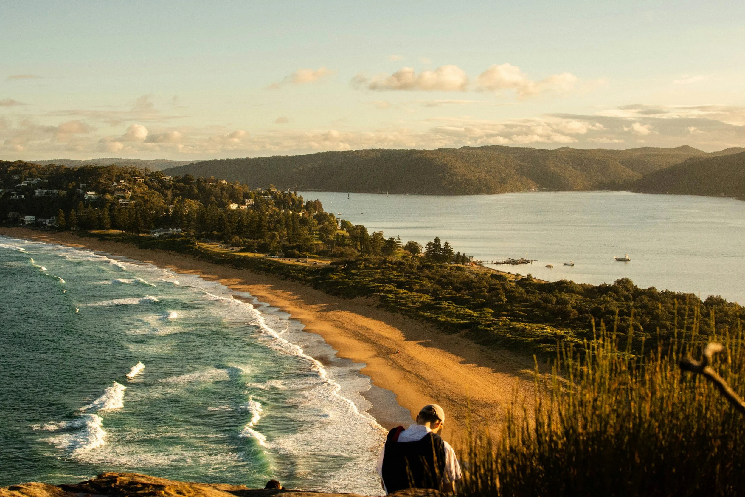 Sunset over a sandy bay with a headland in silhouette