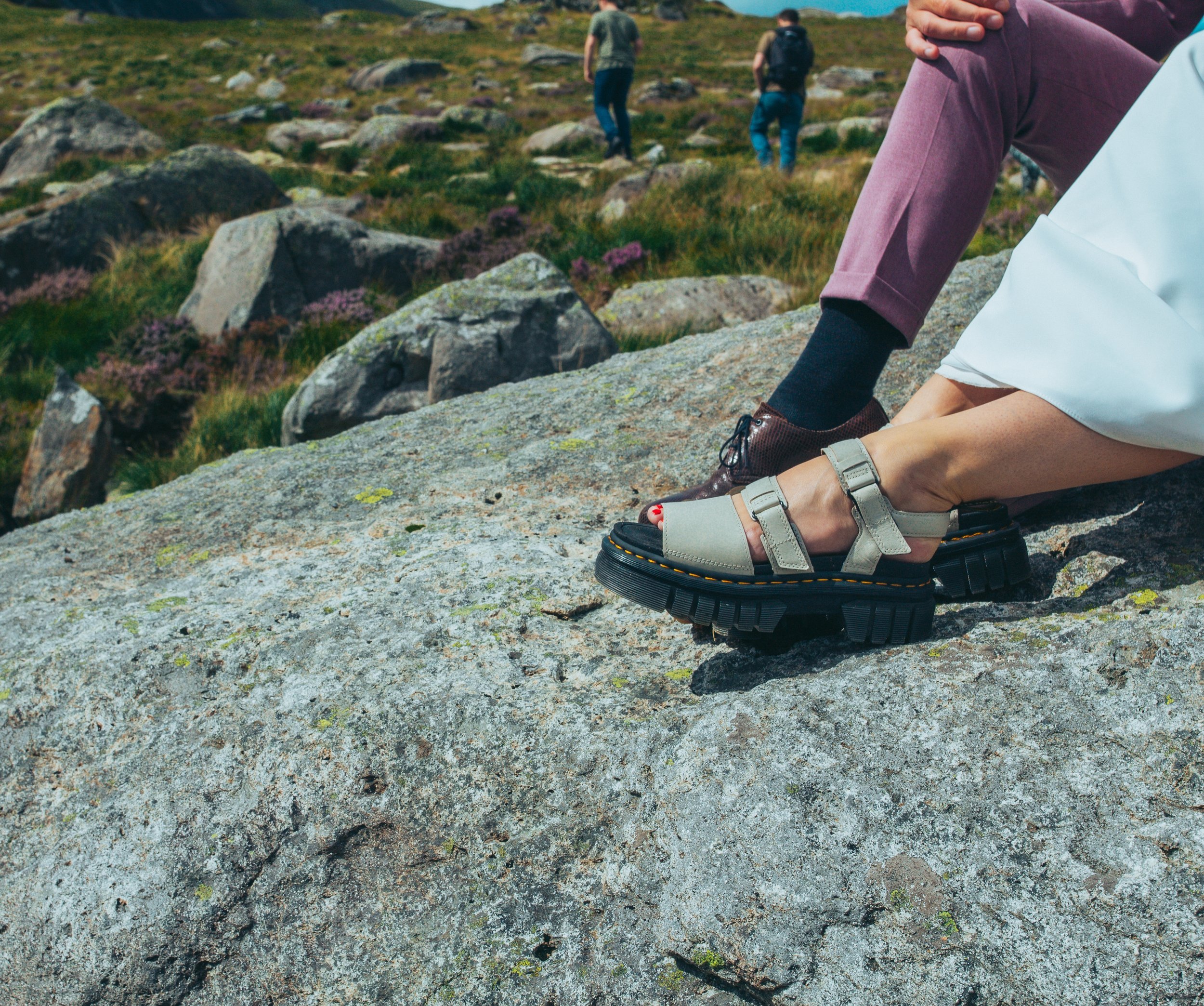 Close-up of a couple's feet resting on a large rock