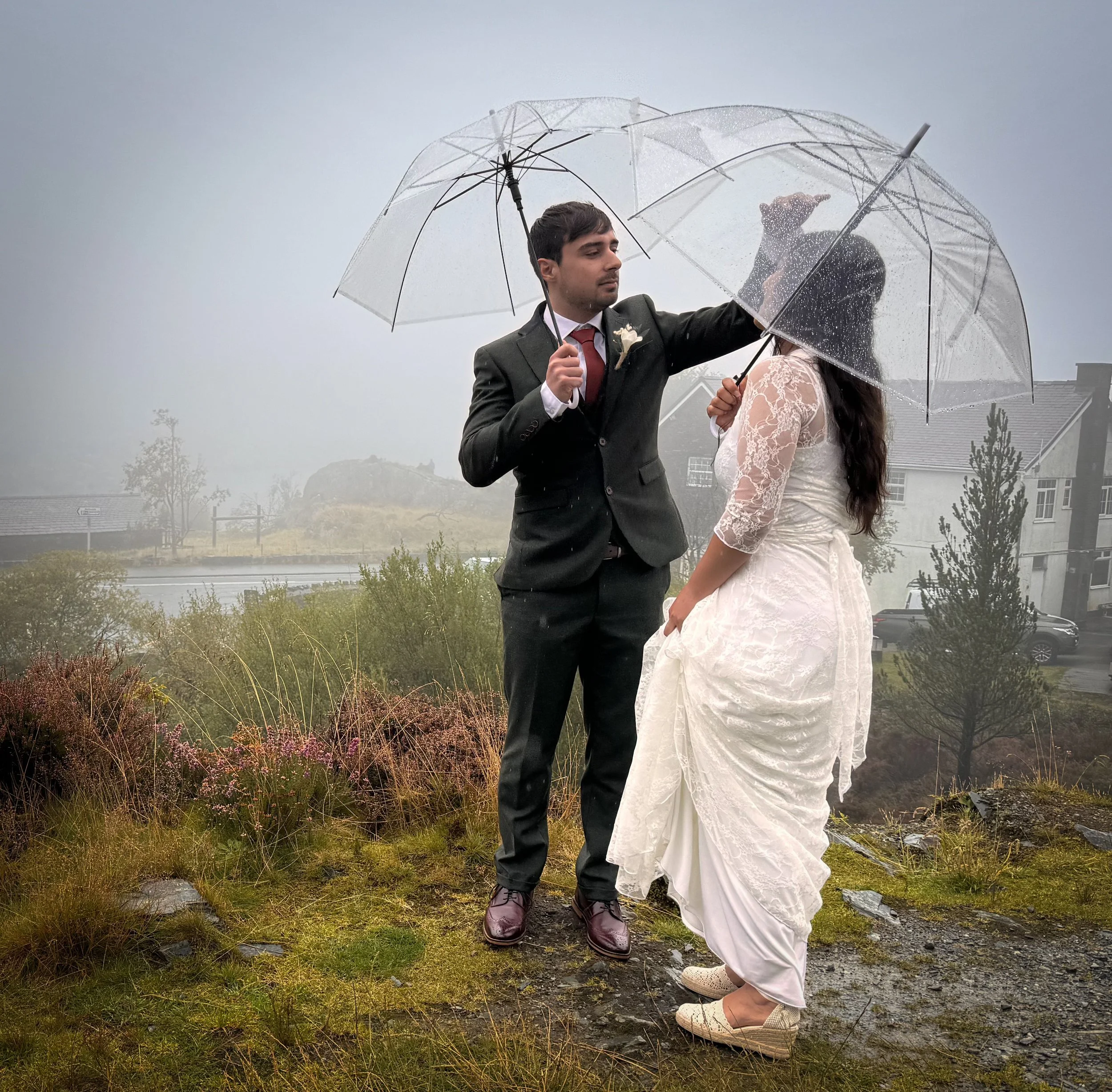A couple sheltering under clear umbrellas on a misty, rainy day