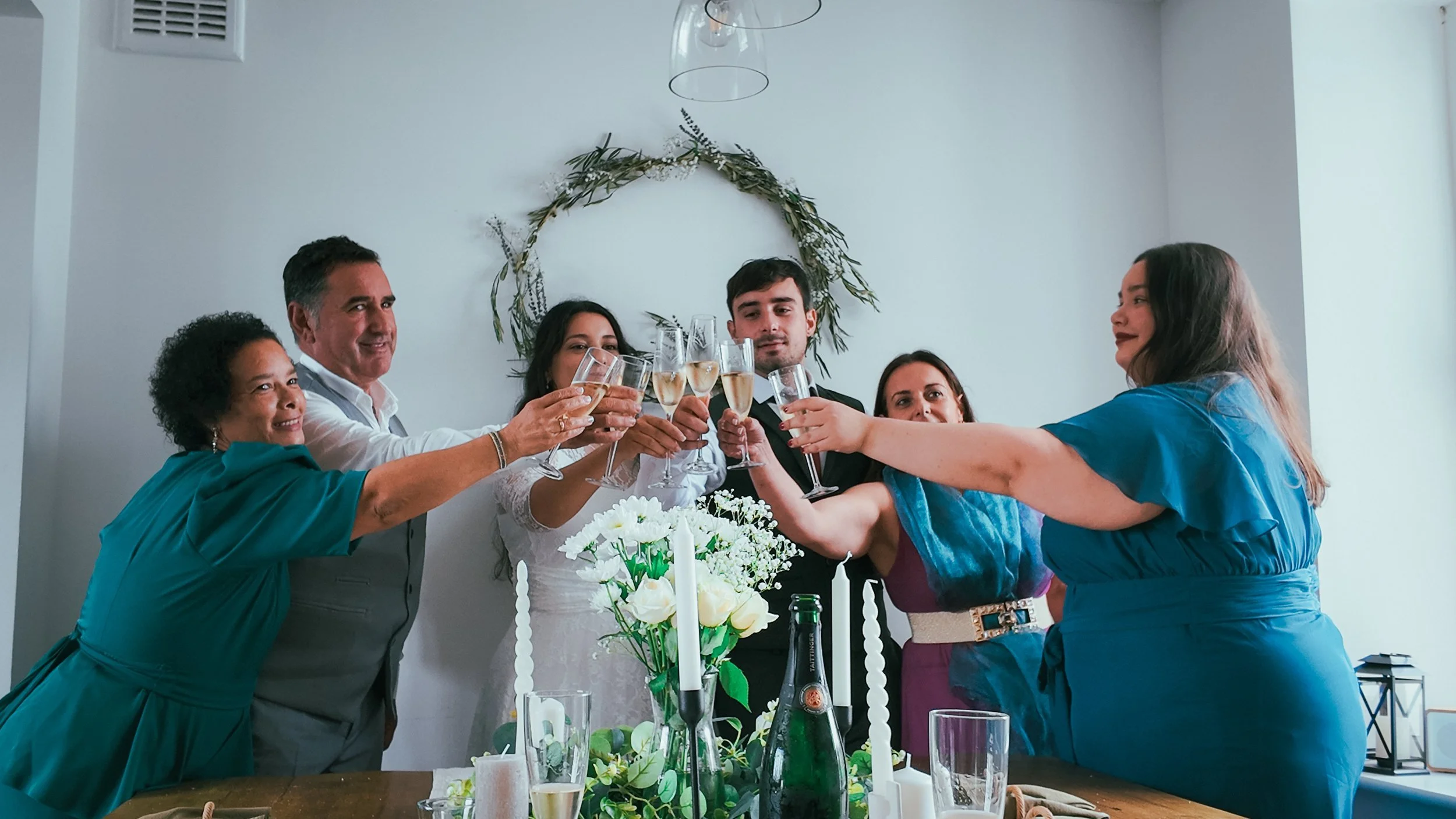 A group of family and friends raising their glasses in a toast with a newly married couple