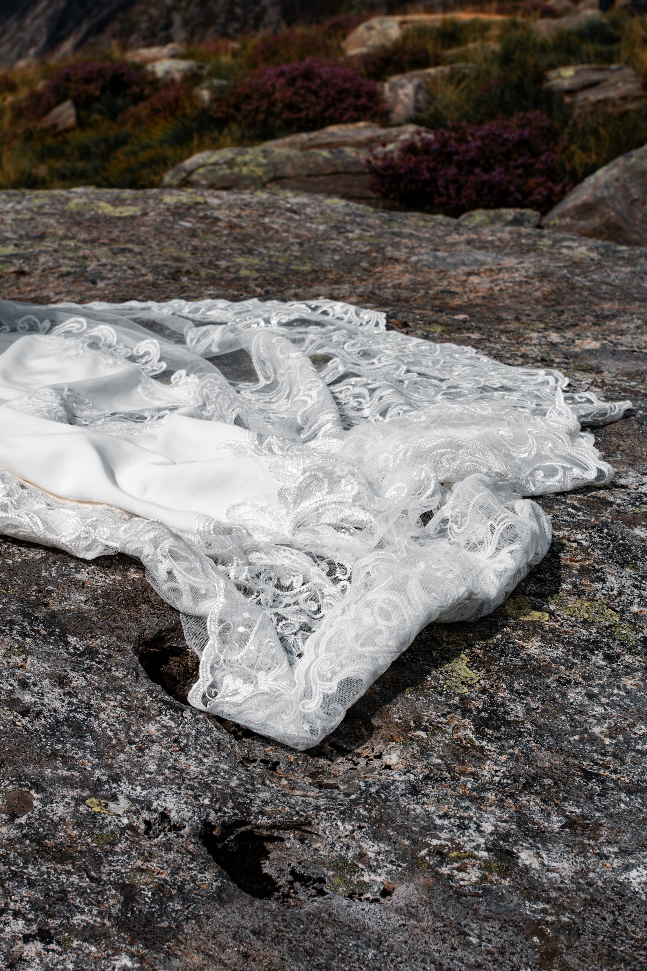 A lace wedding veil laid out on a rock