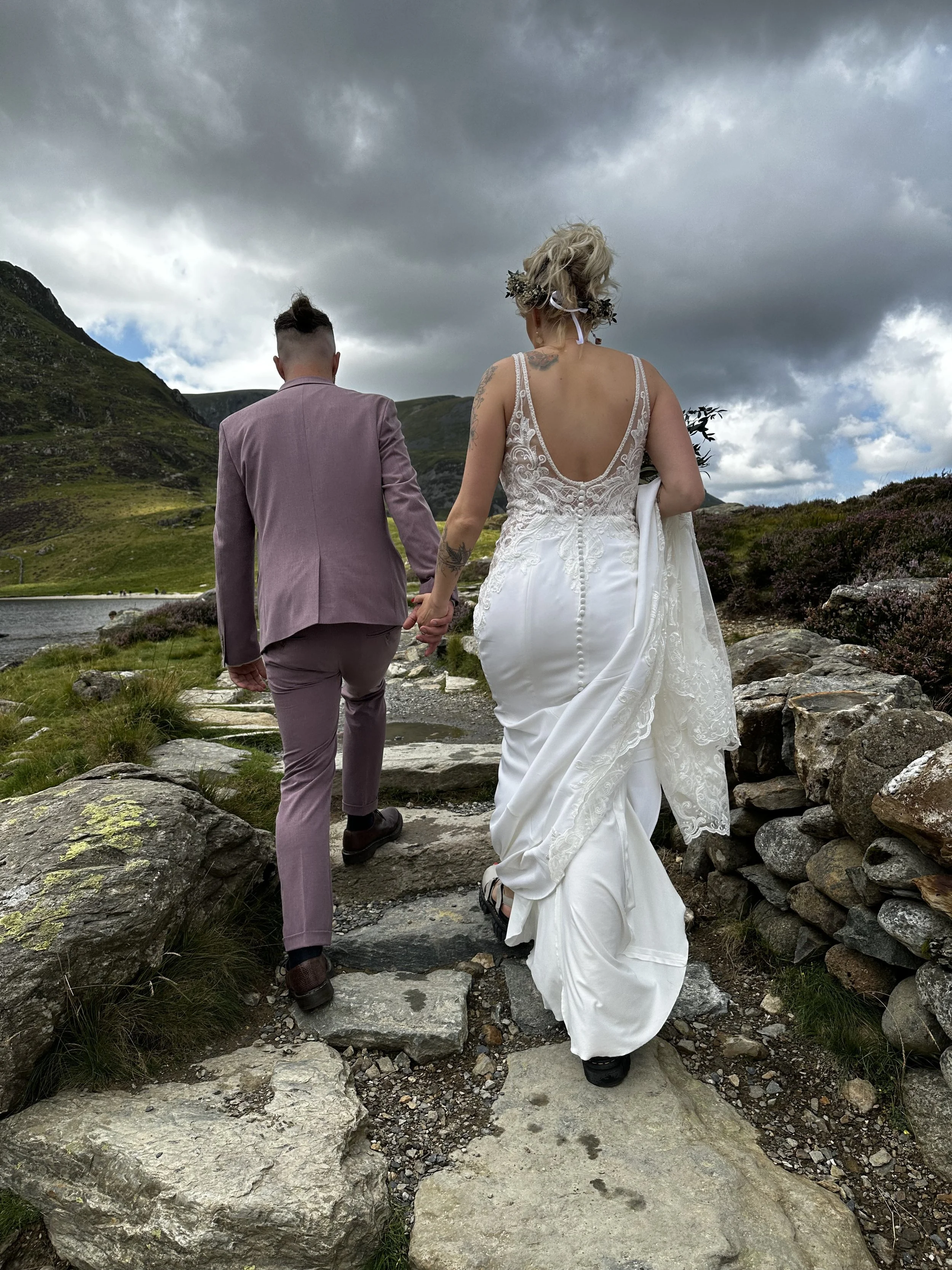 A couple walking hand in hand up a stone mountain path