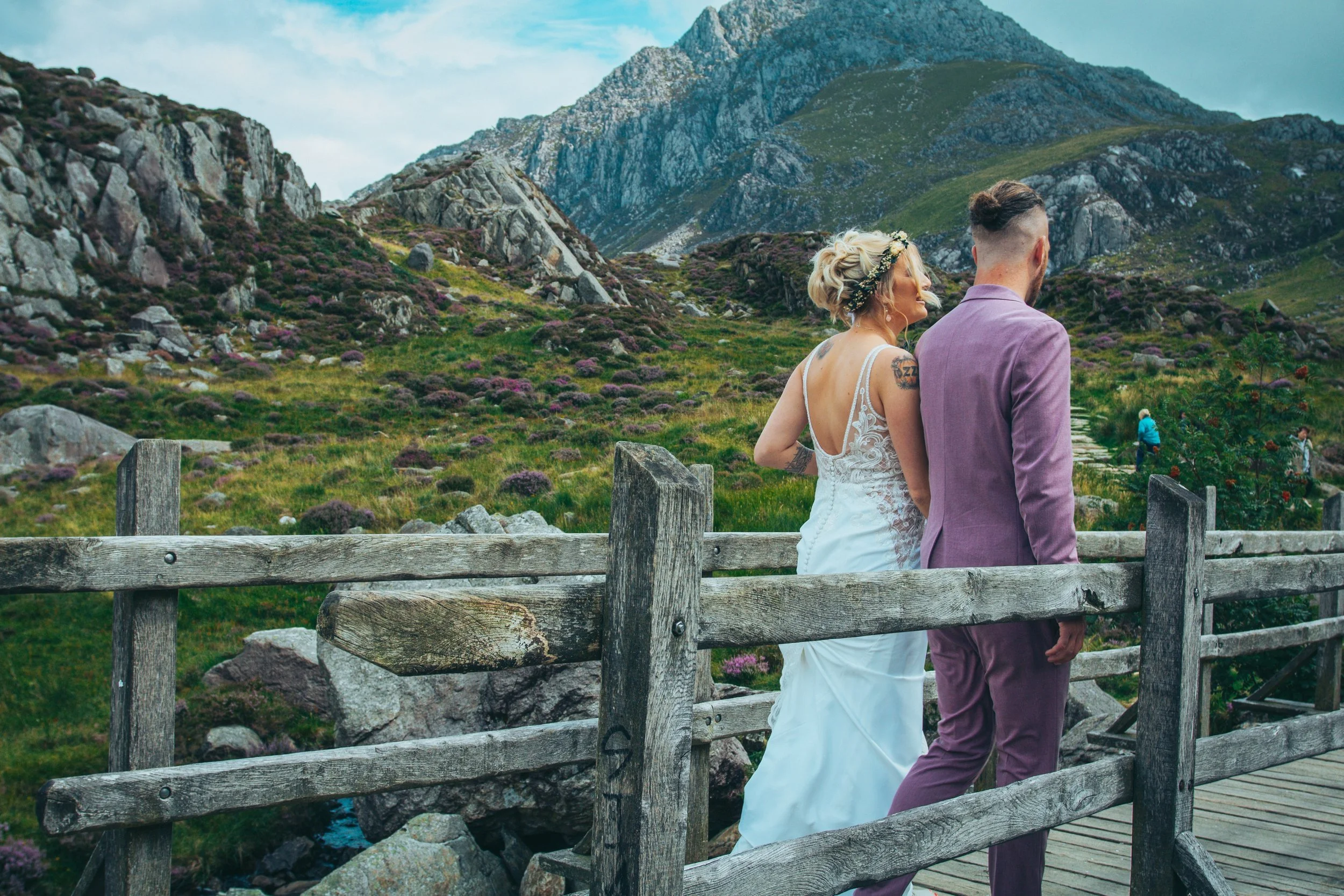 A couple standing by a wooden fence, looking out at the mountains
