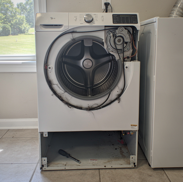 Severed dryer drive belt lying inside empty drum