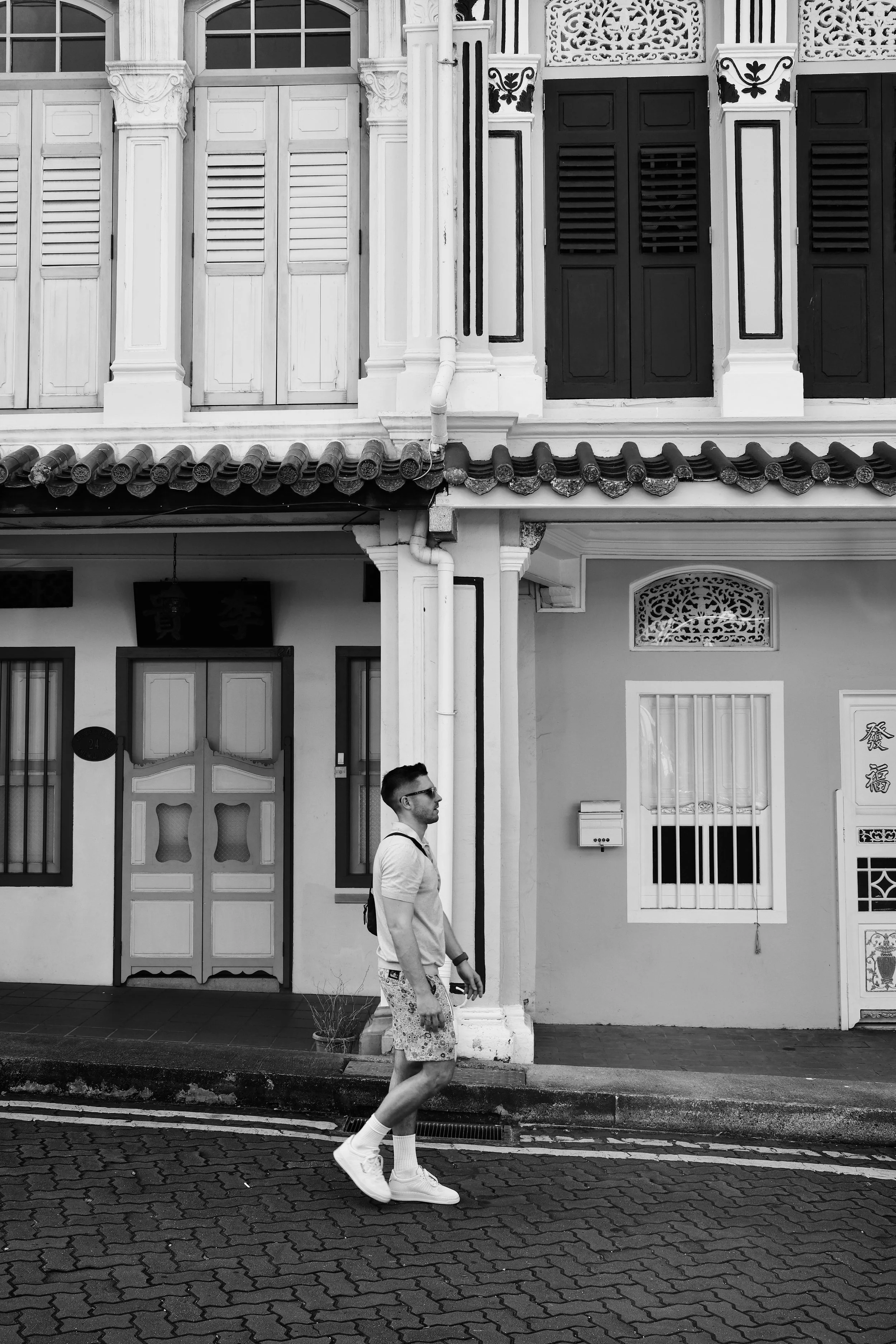 Zwart-wit straatfoto van een man voor historische architectuur in Singapore.
