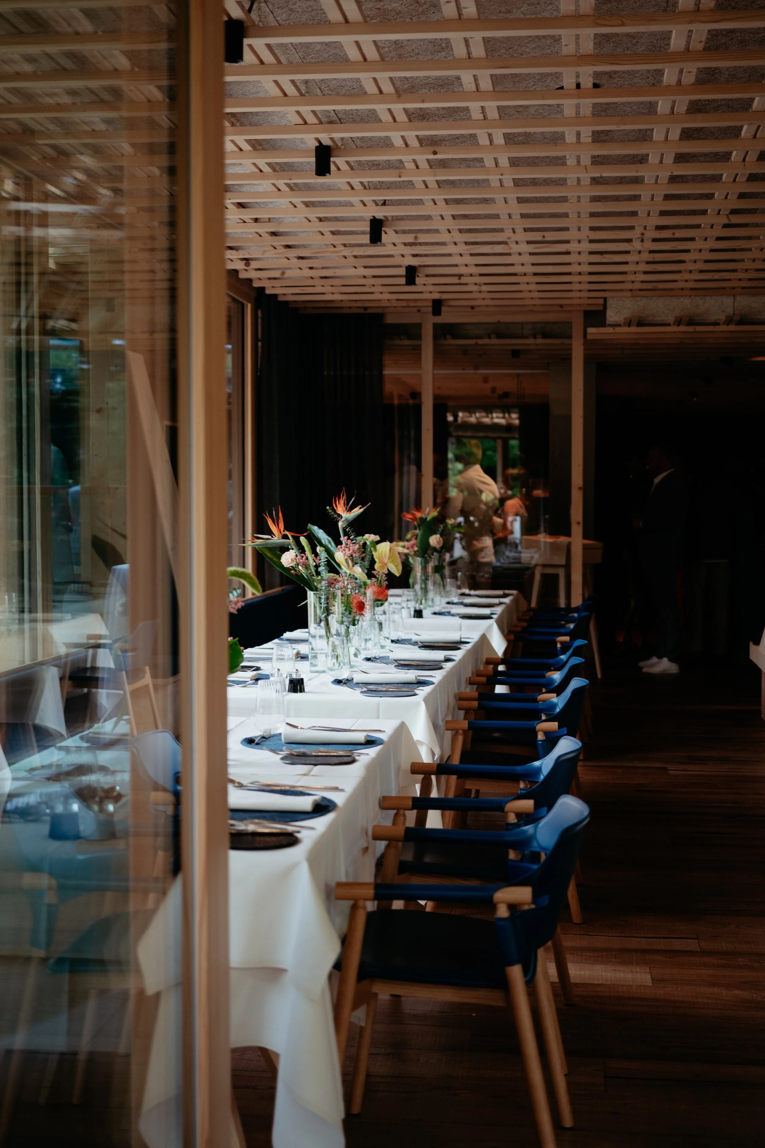 Lange dinertafel met bloemen, stijlvol gedekt voor een bruiloft.
