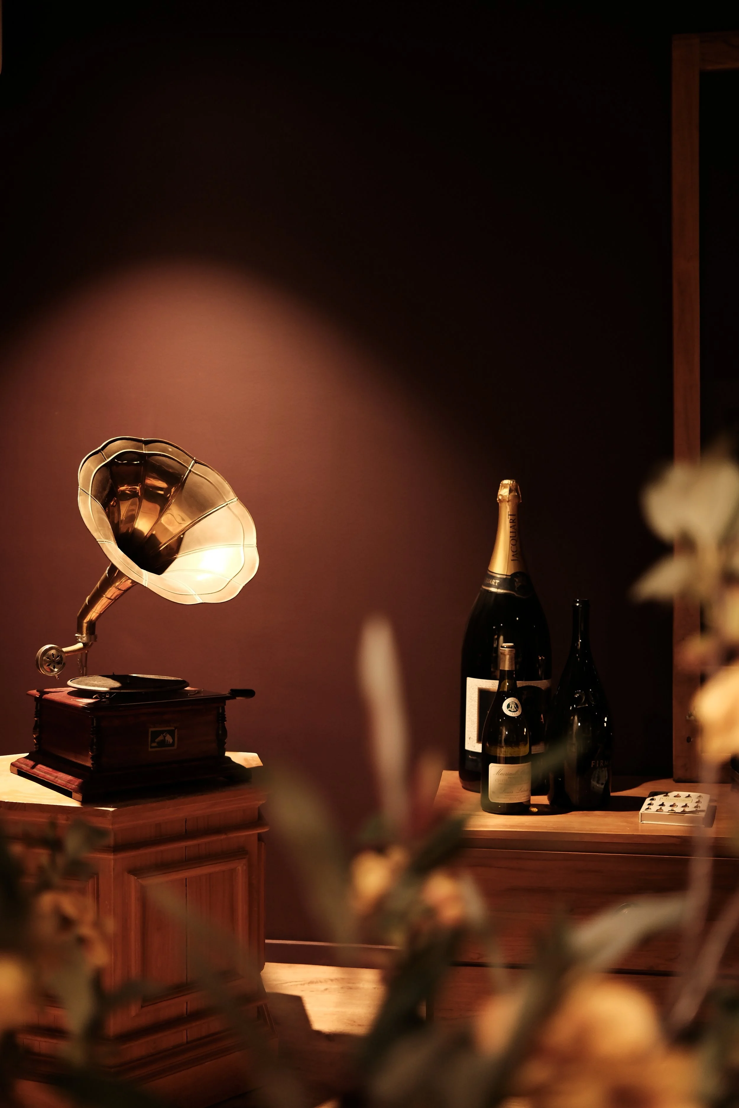 Sfeervolle merkfotografie met een vintage grammofoon en flessen in het warme interieur van &Keur.