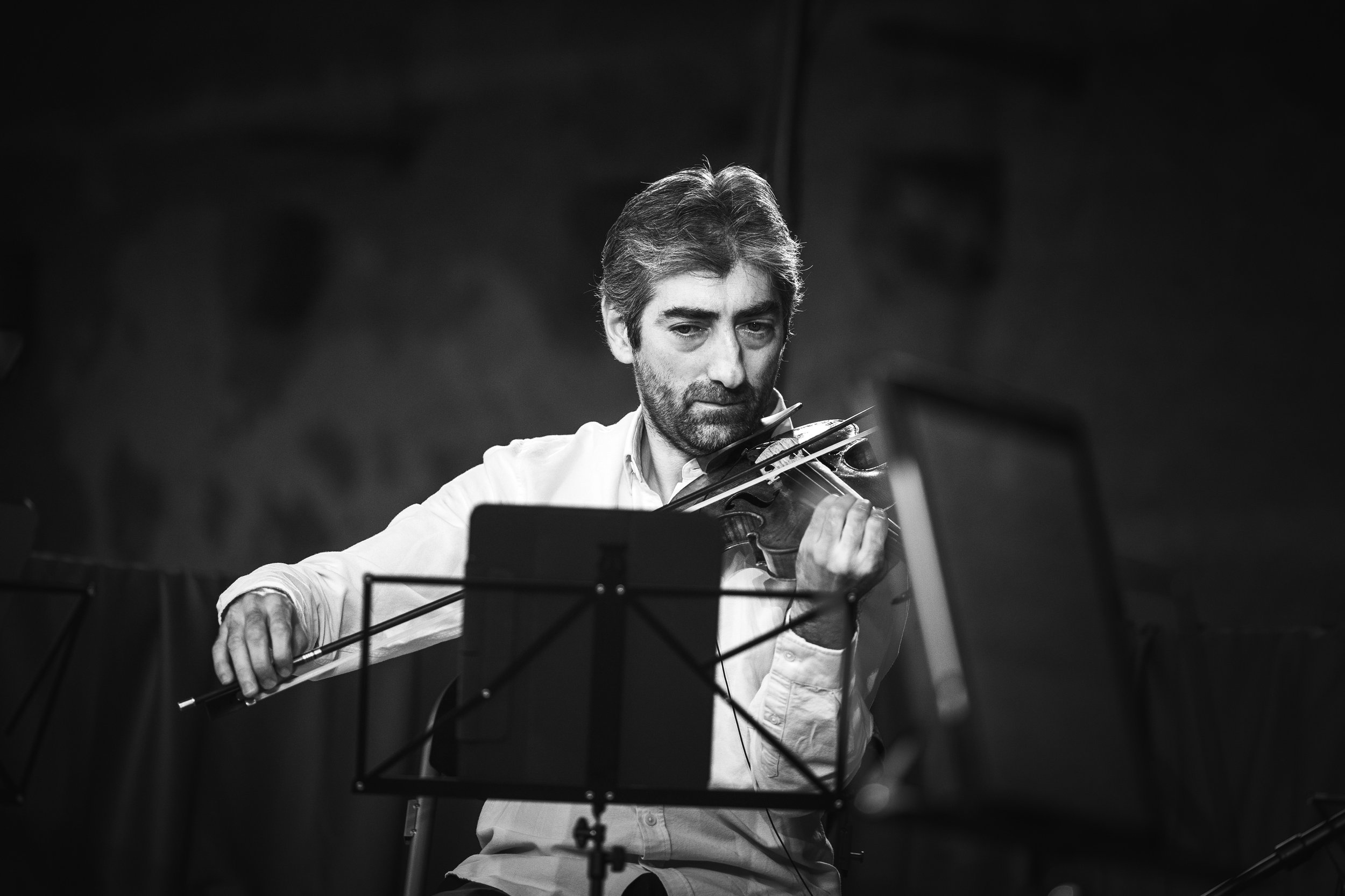 Un homme en train de jouer du violon lors d'une performance, en noir et blanc.