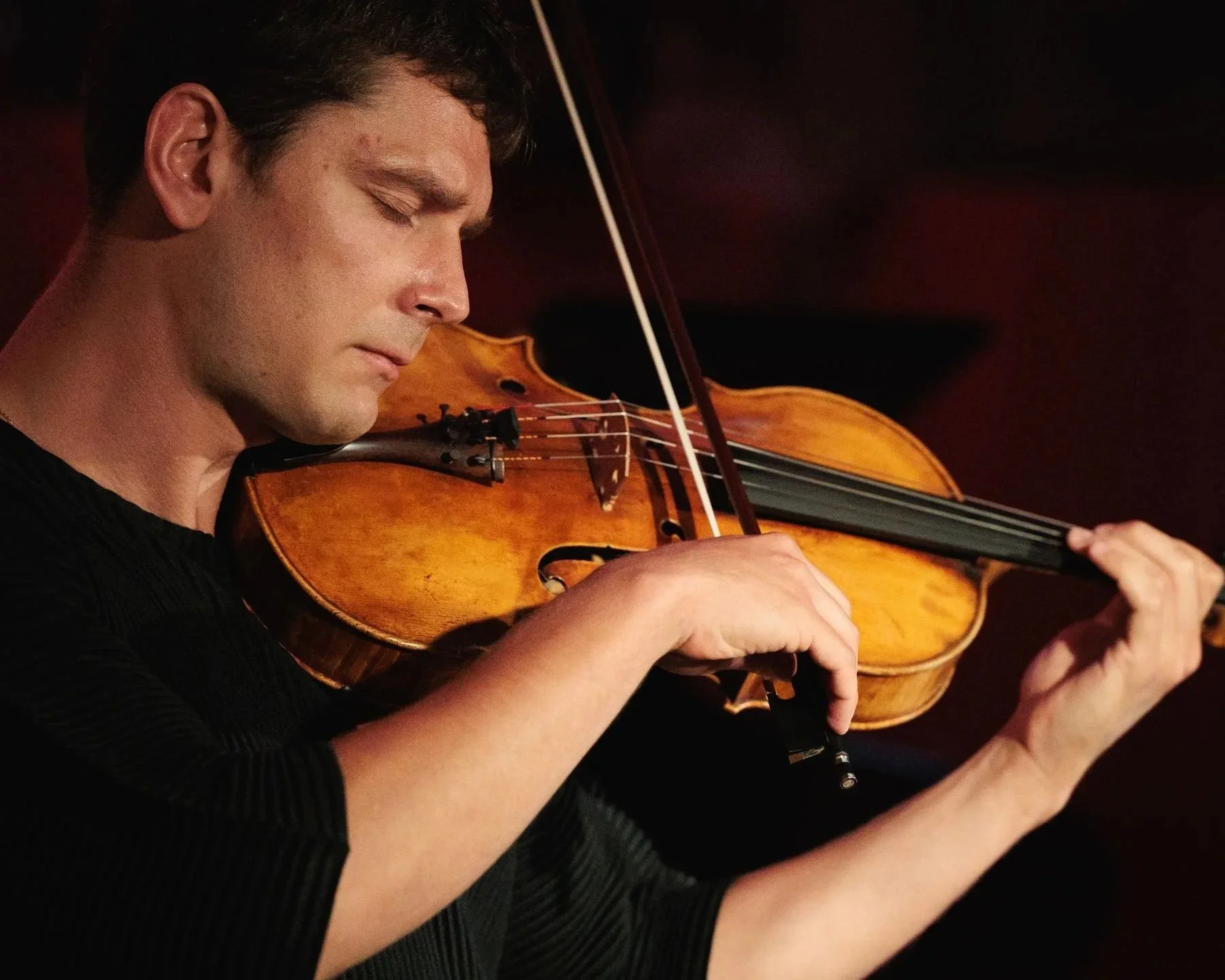 Un homme joue du violon dans l'obscurité.