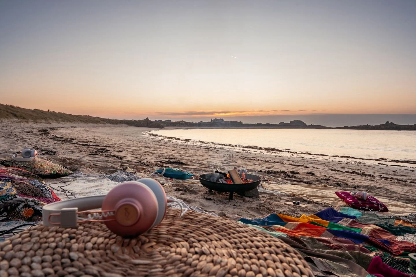 Headphones, cushions and blankets arranged for a CMF session on a Guernsey beach at sunset.