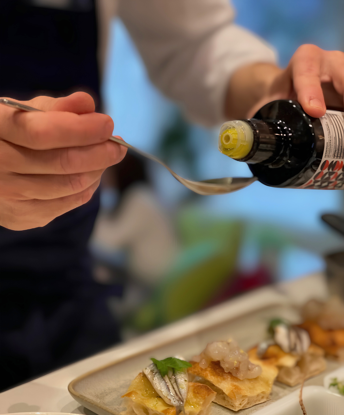 Max che guarnisce un piatto gourmet con olio extra vergine di oliva di alta qualità durante una cena a domicilio