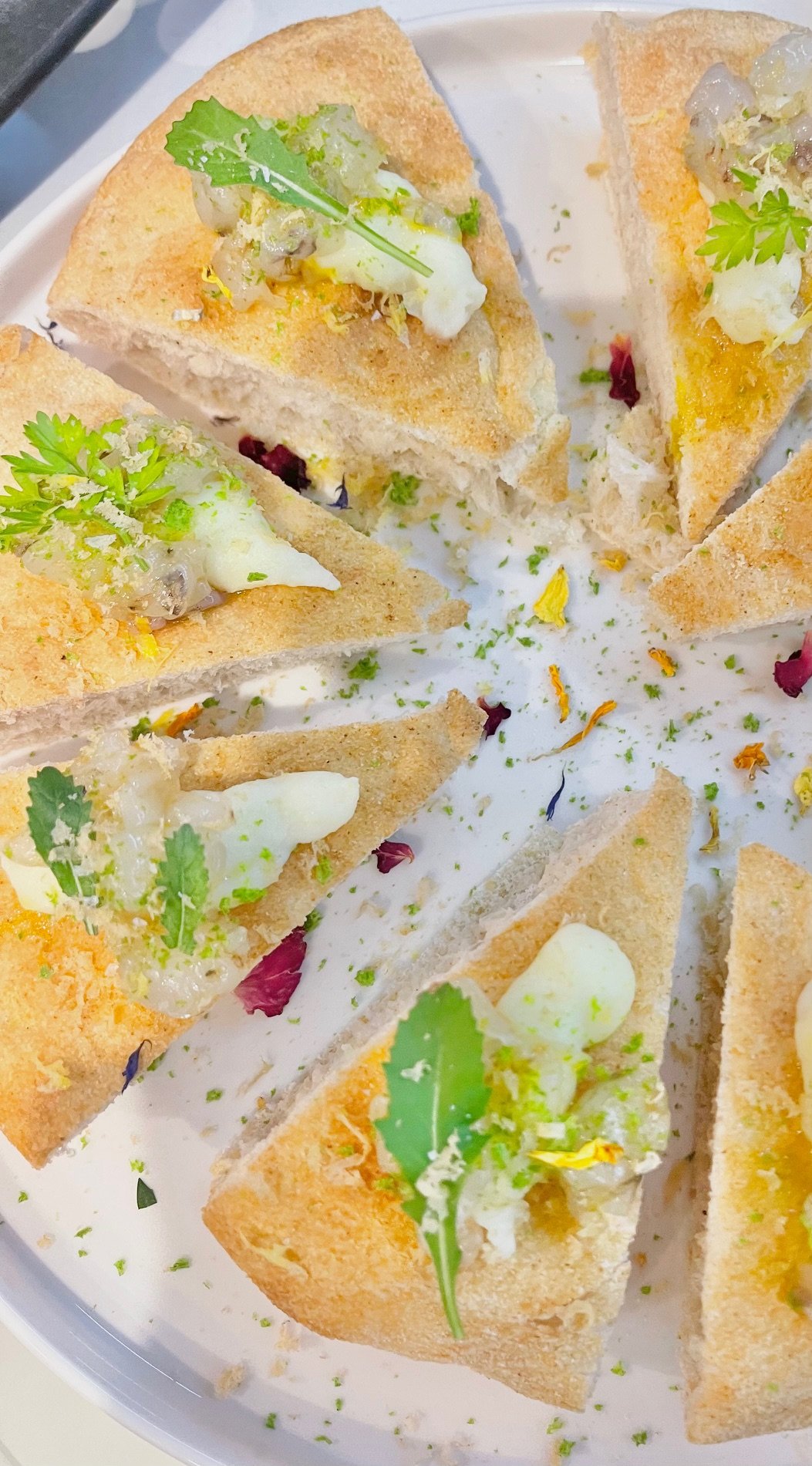 Tartine di pane tostato con crema, erba cipollina, foglie di coriandolo e fiori eduli