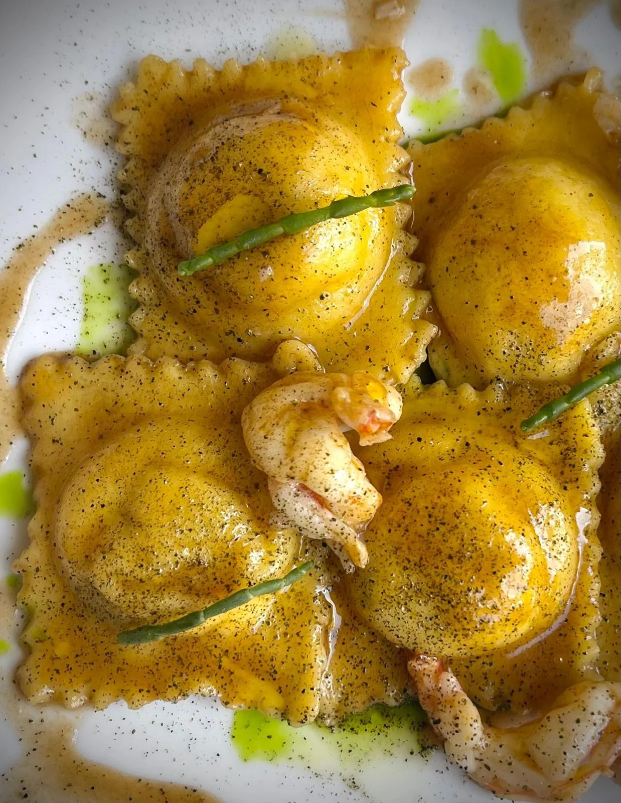 Gamberi e patate novelle con spezie e olio, decorati con piccoli ramoscelli verdi.