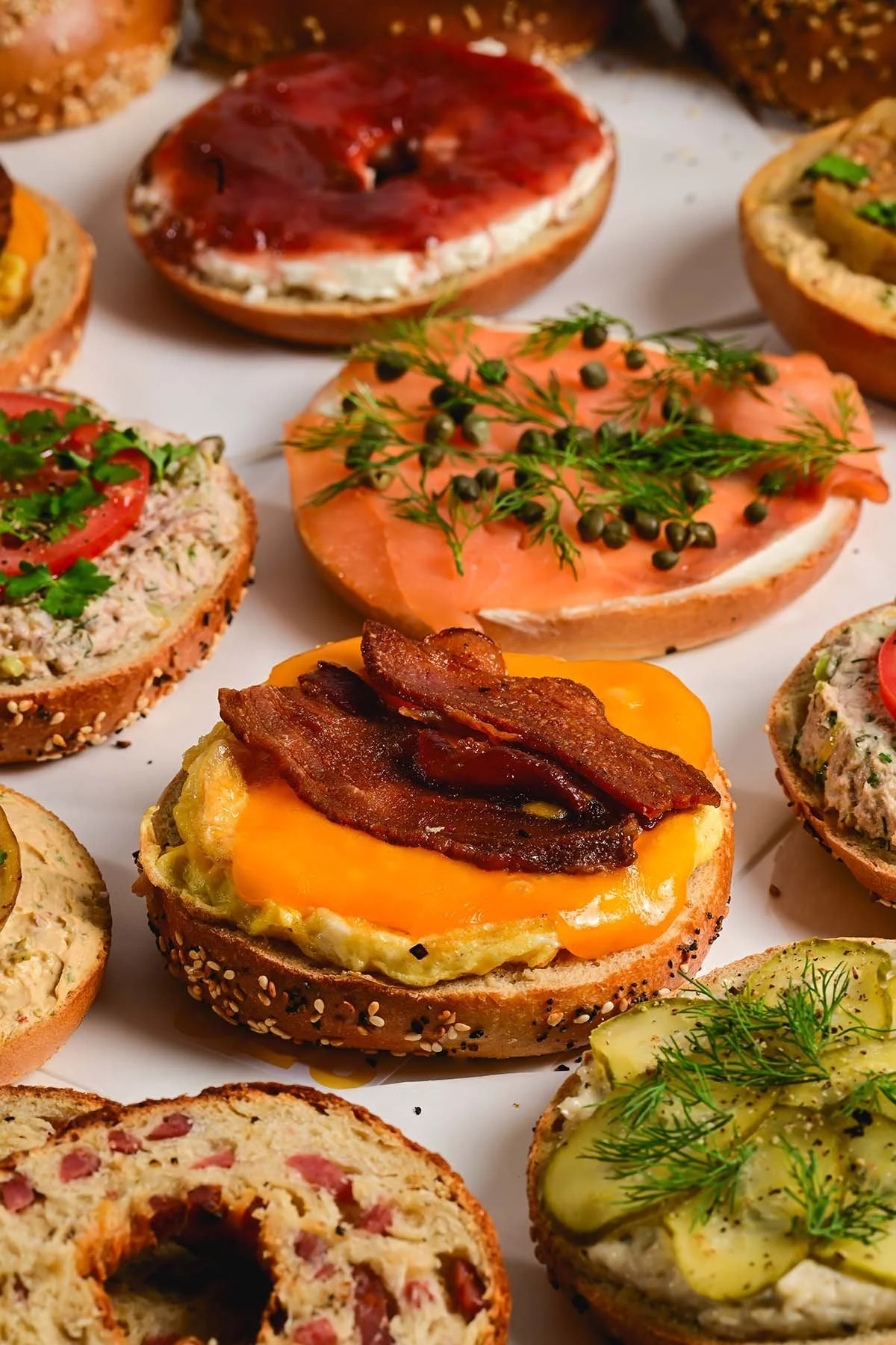 Assorted open-faced sandwiches with various toppings including smoked salmon, bacon, vegetables, herbs, and spreads on different types of bread.