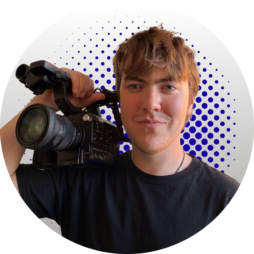 Young man with wavy brown hair holding a professional video camera on his shoulder, standing against a white background with blue dotted design.