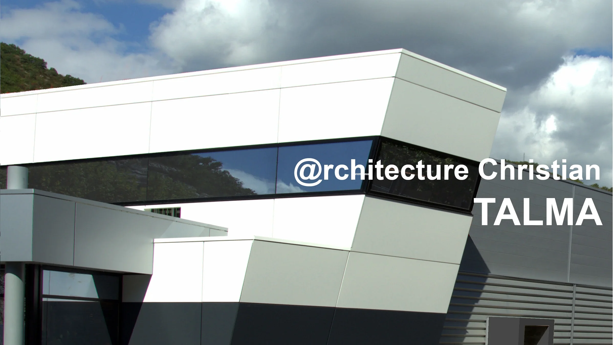 Photo d'un bâtiment moderne blanc avec de grandes fenêtres noires sous un ciel nuageux, avec la mention '@architecture Christian TALMA' en blanc sur l'image.